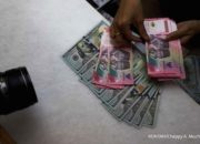 Tampilan layar monitor yang menunjukkan grafik pergerakan nilai tukar mata uang Rupiah terhadap Dolar AS.