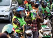 Seorang pengemudi ojek online sedang menunggu penumpang di pinggir jalan Jakarta.