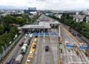 Papan penunjuk jalan tol Jasa Marga dengan latar belakang gedung perkantoran di Jakarta