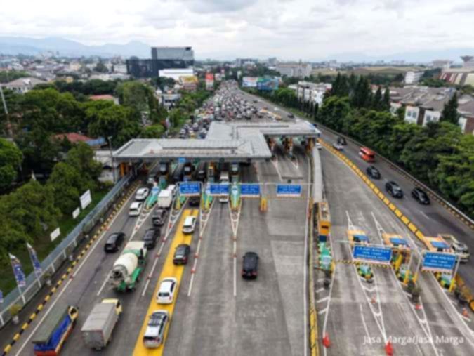 Papan penunjuk jalan tol Jasa Marga dengan latar belakang gedung perkantoran di Jakarta