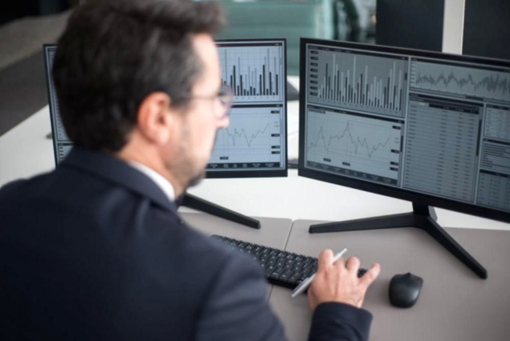 Grafik pergerakan harga saham di layar monitor yang menunjukkan fluktuasi pasar