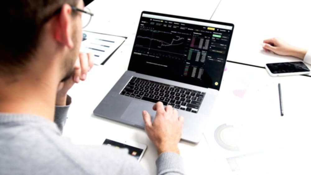 Grafik pergerakan harga saham di layar monitor yang menunjukkan tren kenaikan pasar