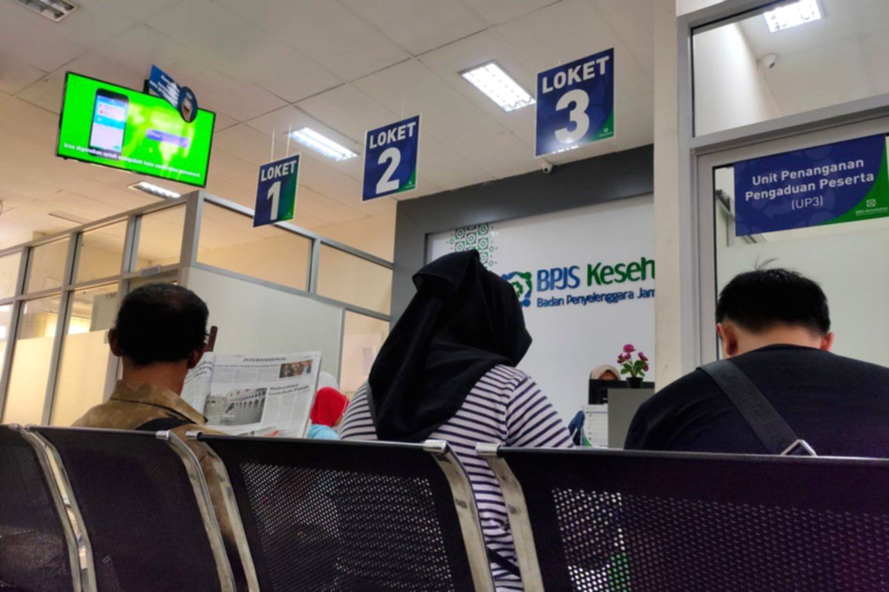 Logo BPJS Kesehatan dengan latar belakang kantor pelayanan publik yang bersih dan modern