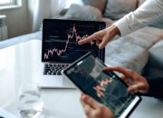 Grafik pergerakan harga saham dan dokumen merger perusahaan di meja kerja investor