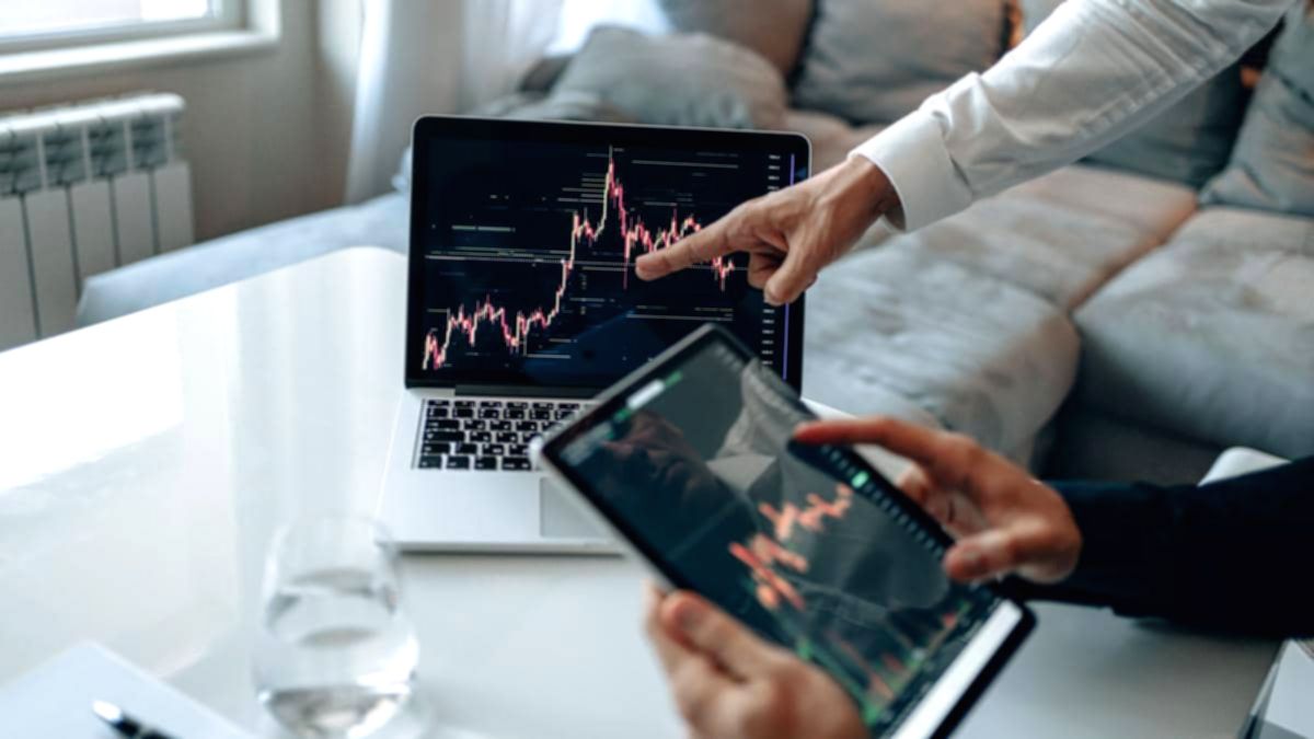Grafik pergerakan harga saham dan dokumen merger perusahaan di meja kerja investor